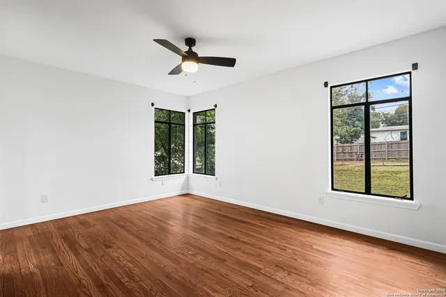 a view of an empty room with wooden floor and a window