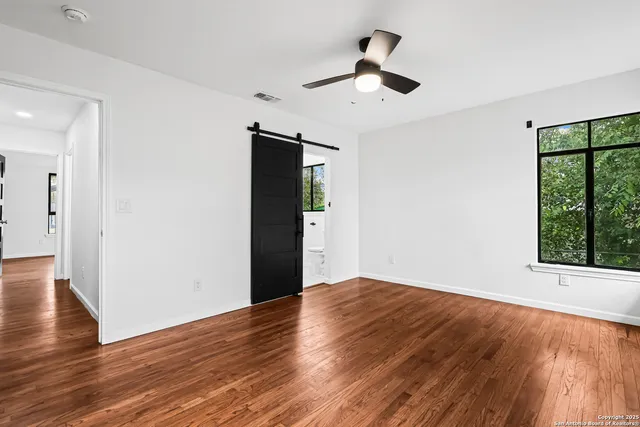 a view of an empty room with wooden floor and a window