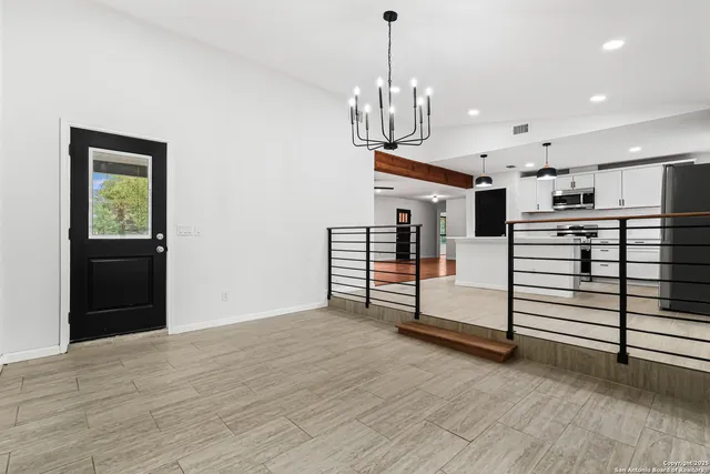 a view of an empty room with window and chandelier