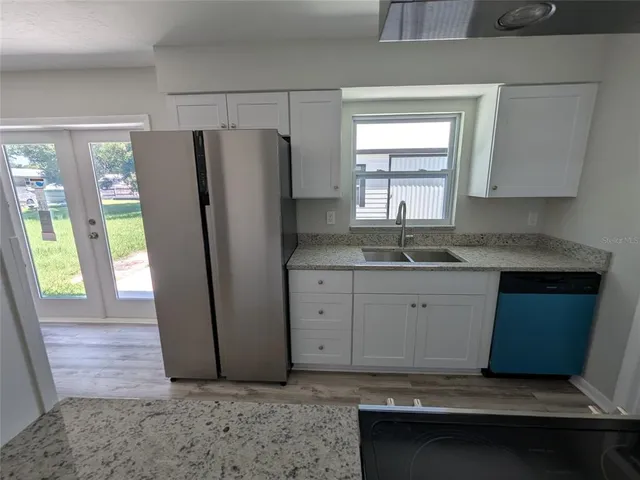 a kitchen with granite countertop a sink window and cabinets