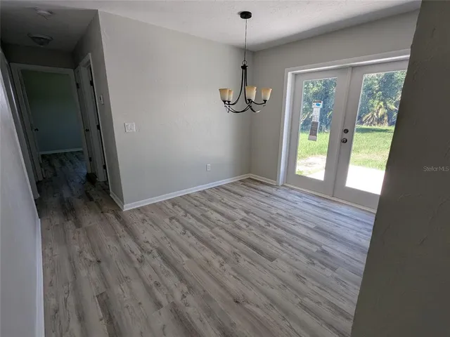 an empty room with wooden floor windows and fireplace