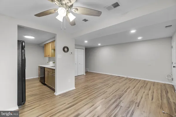 a view of an empty room with wooden floor and a ceiling fan