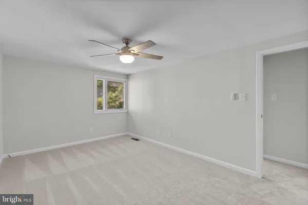 an empty room with a window and a fan