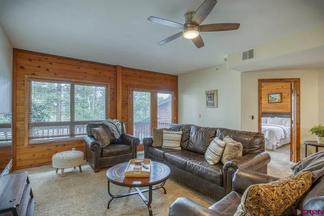 a living room with furniture a flat screen tv and a large window