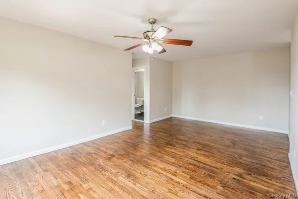 a view of a room with wooden floor and a ceiling fan