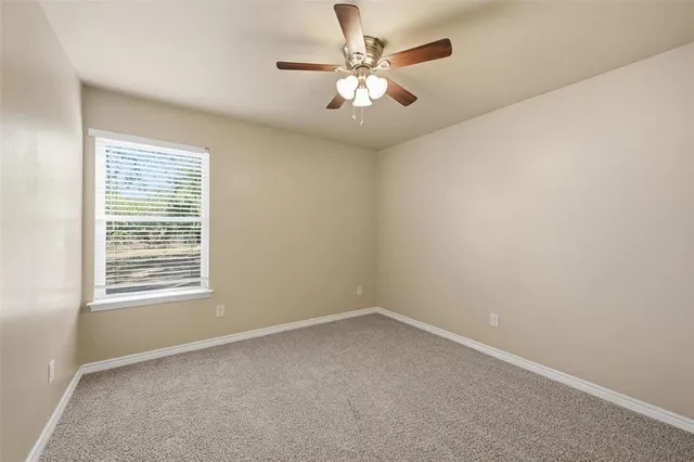 an empty room with a chandelier fan and windows