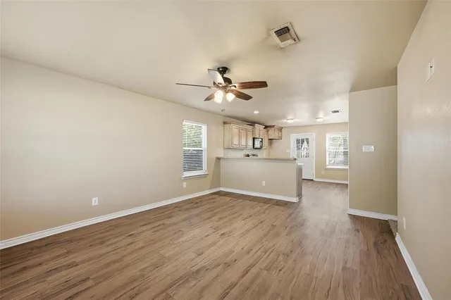 a view of a kitchen with a fridge wooden floor and a ceiling fan