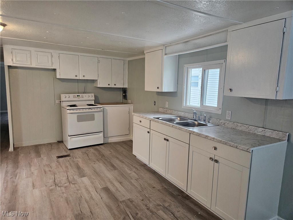 2305 East Waterloo Road Akron, OH 44312 - Photo 2 of 12 Kitchen with electric stove, white cabinets, light countertops, a textured ceiling, and light wood-style flooring