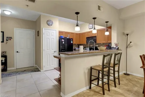 a kitchen with kitchen island granite countertop a table chairs refrigerator and a sink