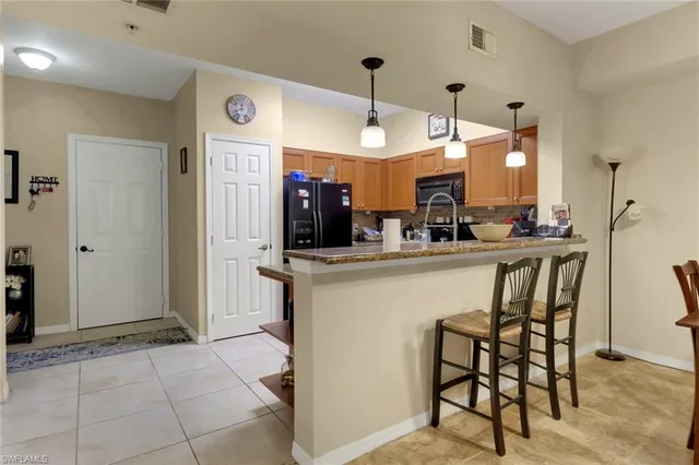 a kitchen with kitchen island granite countertop a table chairs refrigerator and a sink