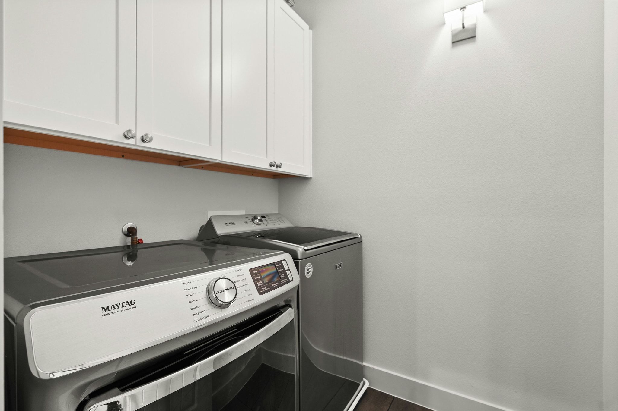 8110 Ranch Road 2222, Unit 92 Austin, TX 78730 - Photo 25 of 40 Laundry area featuring white shaker-style cabinetry with chrome hardware, an integrated wall sconce, and wood-finish flooring