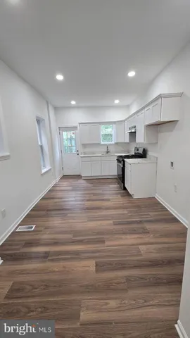 a view of a kitchen with kitchen island a sink wooden floor and a counter top space