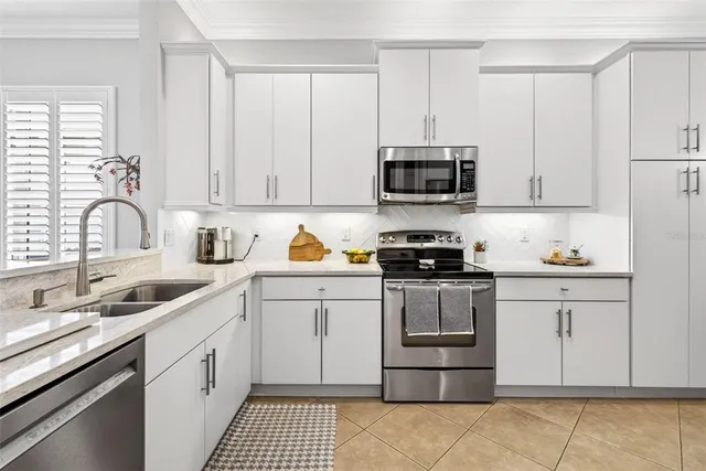 a kitchen with stainless steel appliances granite countertop a stove a sink dishwasher and white cabinets with wooden floor