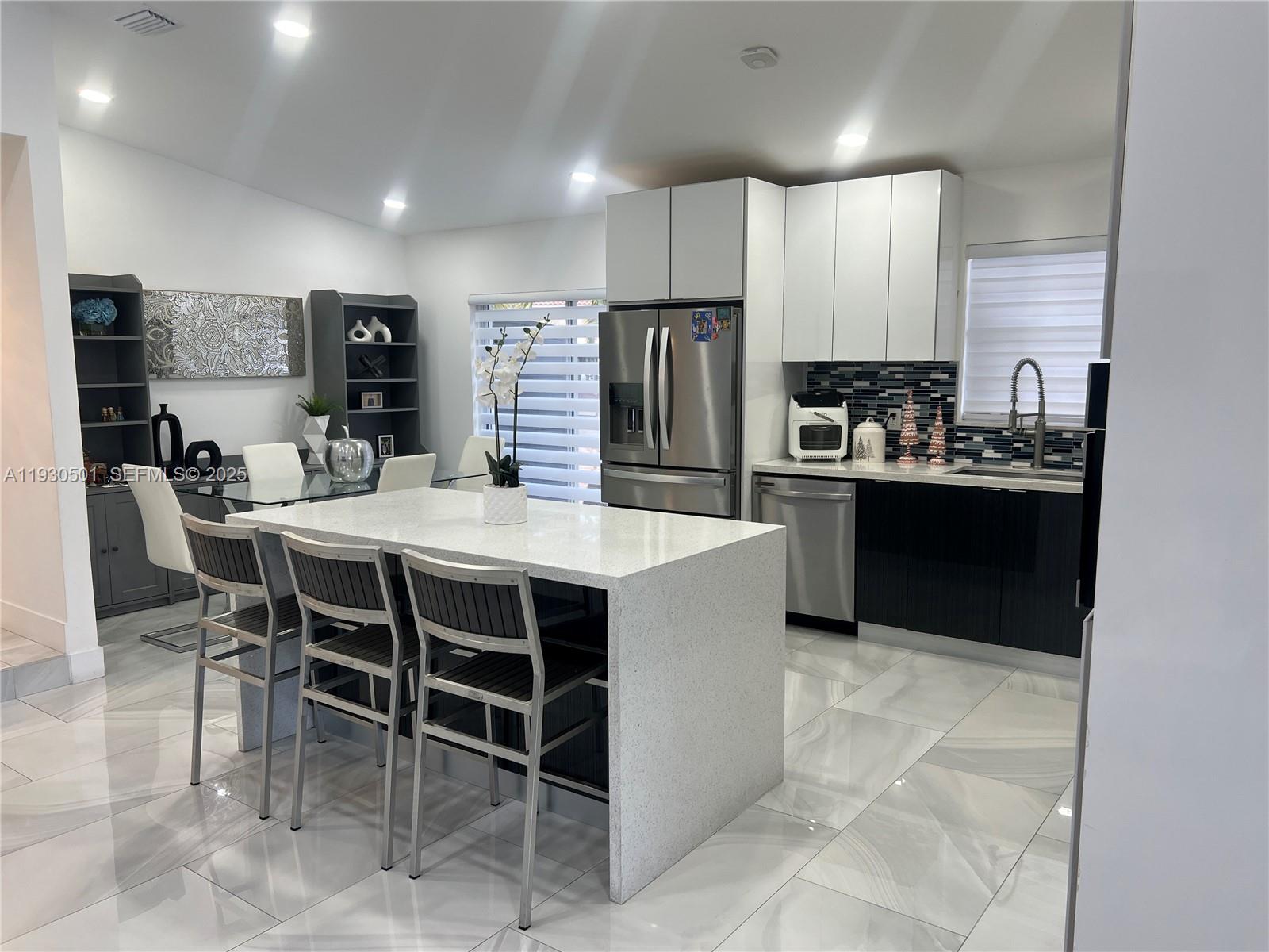 6101 Southwest 153rd Court Road Miami, FL 33193 - Photo 41 of 49 a kitchen with stainless steel appliances kitchen island granite countertop a table chairs and a refrigerator