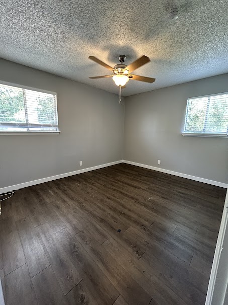 3436 Willowrun Drive, Unit D Austin, TX 78704 - Photo 6 of 9 an empty room with wooden floor fan and windows