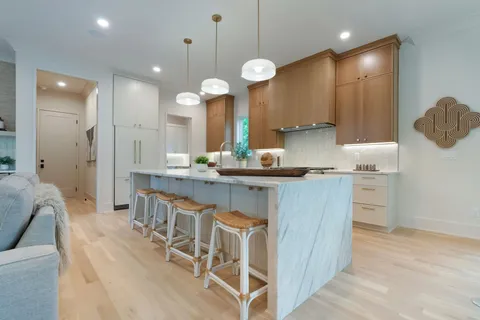 a large kitchen with kitchen island a stove a sink a center island and living room view