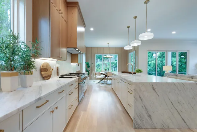 a kitchen with stainless steel appliances granite countertop a table chairs and a large window