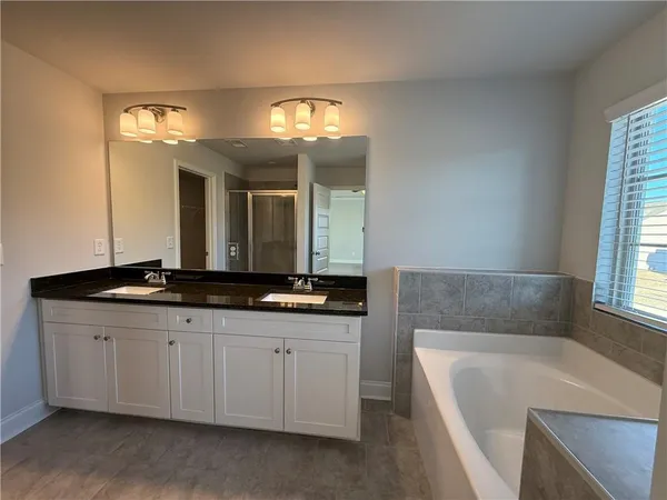 a bathroom with a granite countertop sink a large mirror and a bathtub