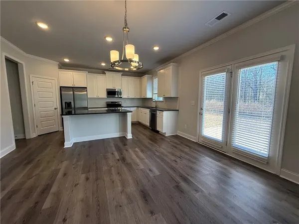 a view of a kitchen with granite countertop wooden floor stainless steel appliances and a window
