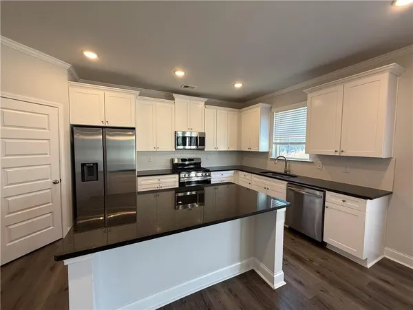 a kitchen with granite countertop a refrigerator and a sink
