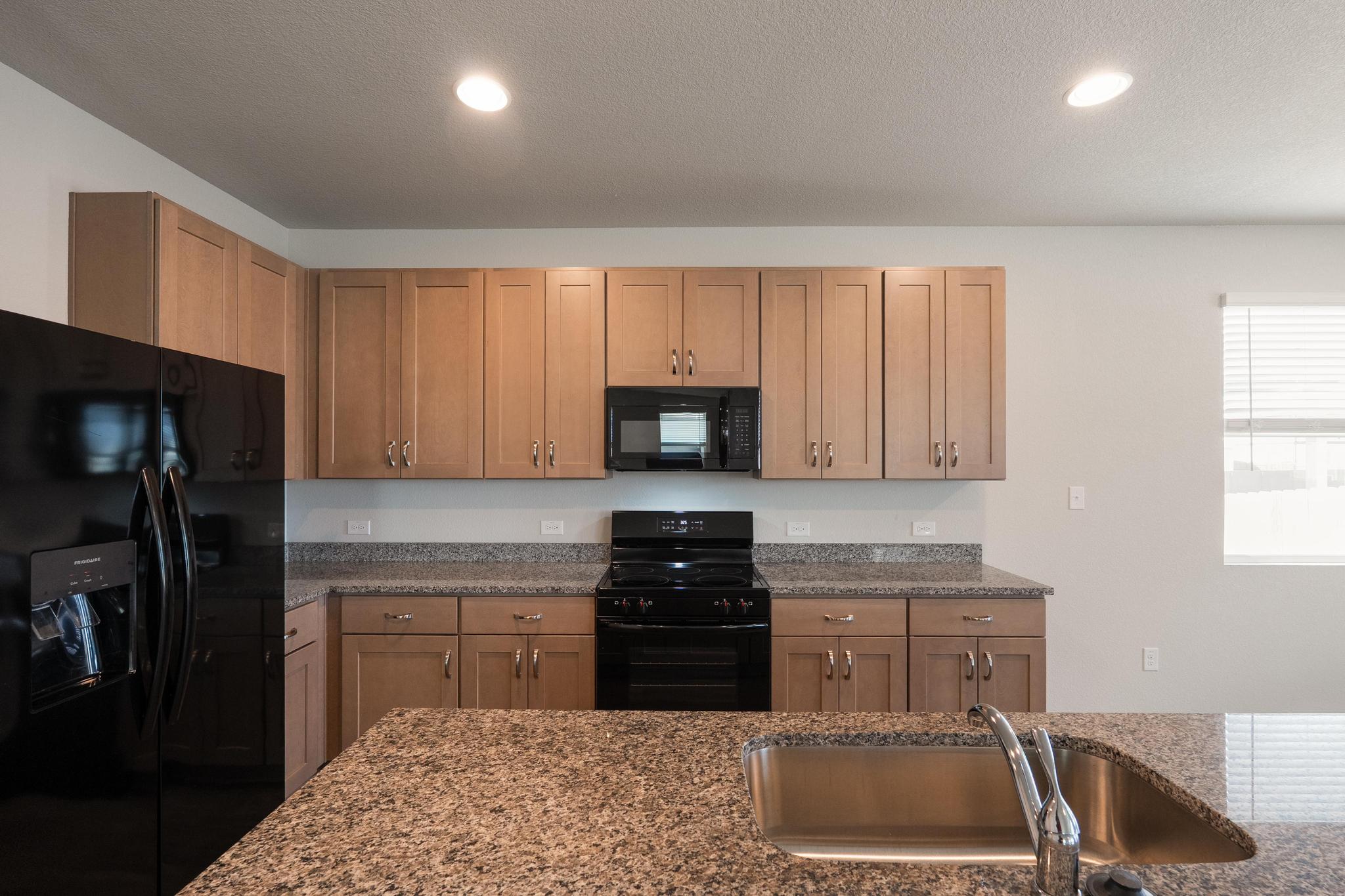 2812 Steels Road Manor, TX 78653 - Photo 10 of 25 Granite countertops and classic wood cabinetry define this functional kitchen space.