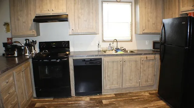 a kitchen with granite countertop a refrigerator a stove a sink and a window