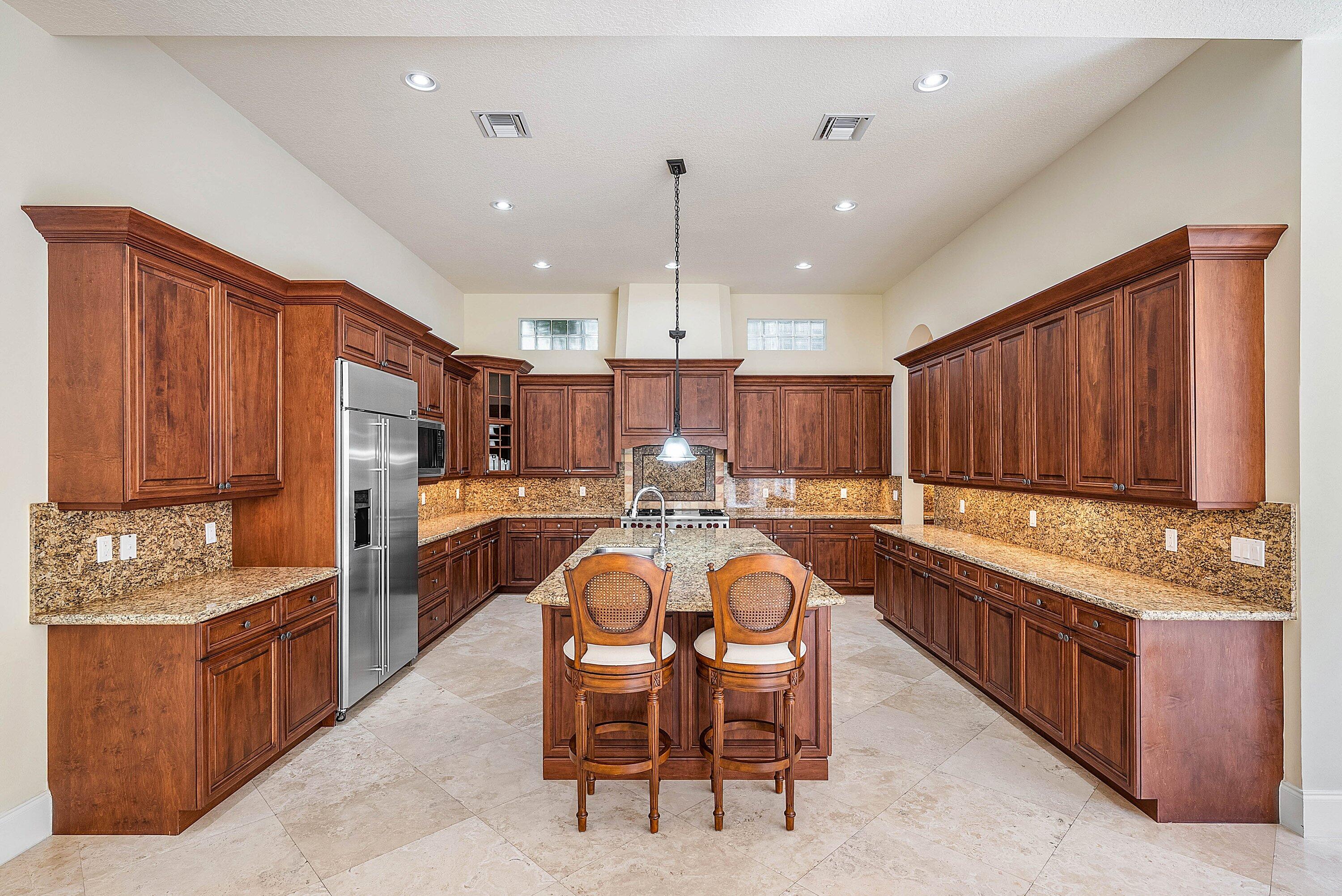 17387 Balaria Street Boca Raton, FL 33496 - Photo 20 of 65 a kitchen with stainless steel appliances kitchen island granite countertop a table chairs and a refrigerator