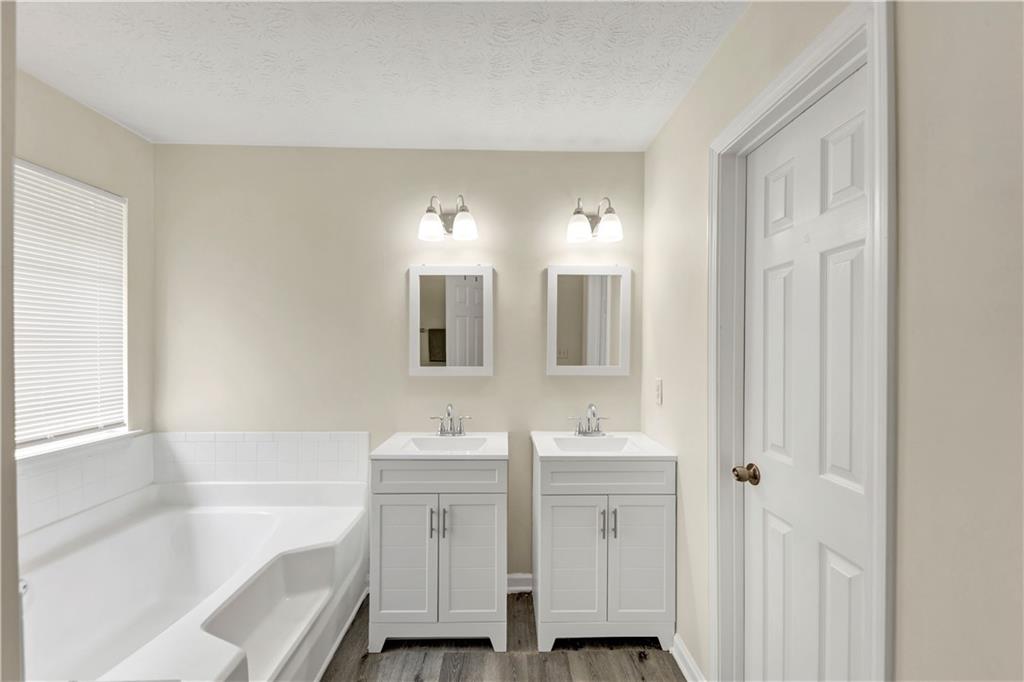 2880 Field Spring Drive Lithonia, GA 30058 - Photo 27 of 31 a bathroom with a double vanity sink a mirror and a bathtub