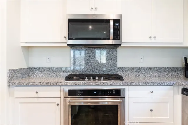 a kitchen with granite countertop white cabinets and a sink