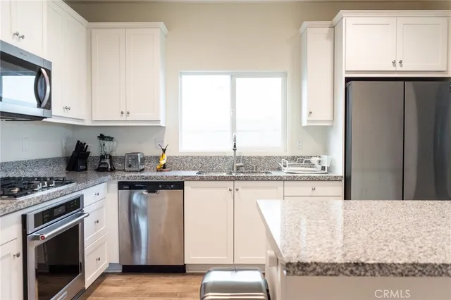 a kitchen with stainless steel appliances granite countertop a refrigerator a stove and a sink