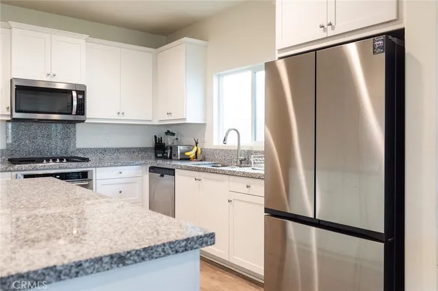 a kitchen with granite countertop stainless steel appliances a stove and a refrigerator