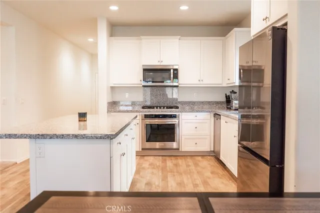 a kitchen with stainless steel appliances granite countertop a refrigerator stove a sink and white cabinets