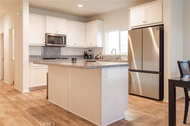 a living room with stainless steel appliances kitchen island a table and chairs