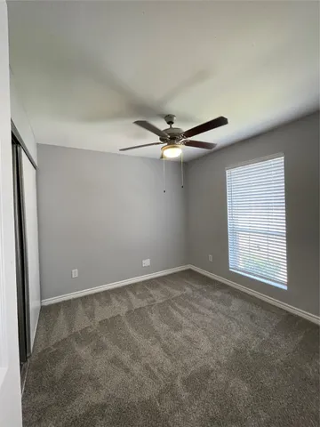 an empty room with windows and ceiling fan