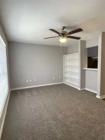 an empty room with a ceiling fan and windows