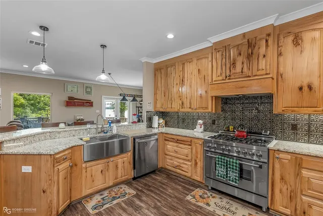 a kitchen with stainless steel appliances granite countertop a sink a stove and a wooden cabinets