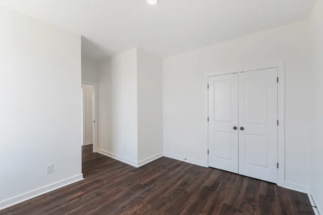 a view of an empty room with closet and wooden floor