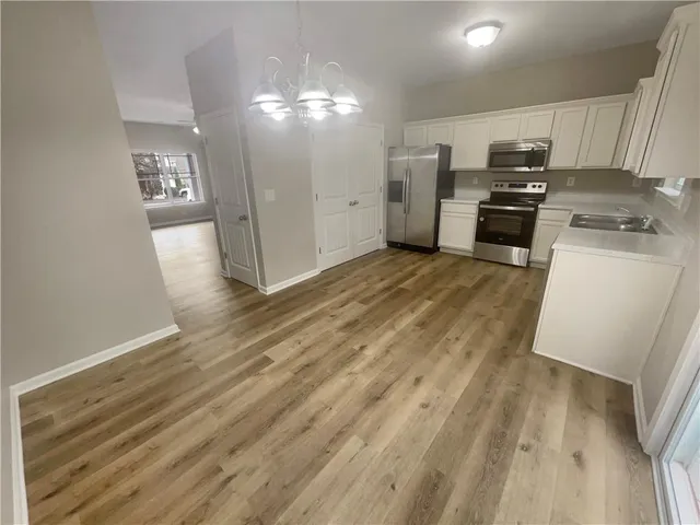 a view of a kitchen with refrigerator and wooden floor
