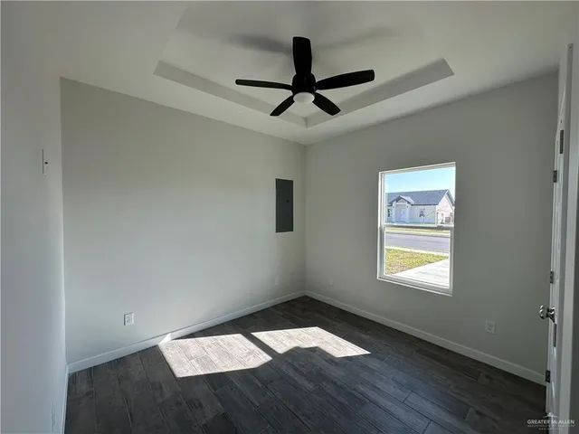 a view of empty room with wooden floor and fan