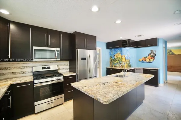 a kitchen with stainless steel appliances kitchen island granite countertop a stove refrigerator and microwave