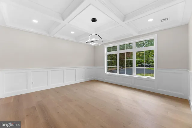 a view of an empty room with wooden floor and windows
