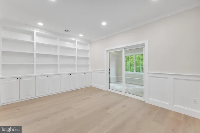 a view of an empty room with a window and a kitchen