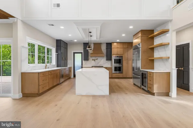 a large kitchen with stainless steel appliances a large counter top a stove a chimney a sink and a refrigerator