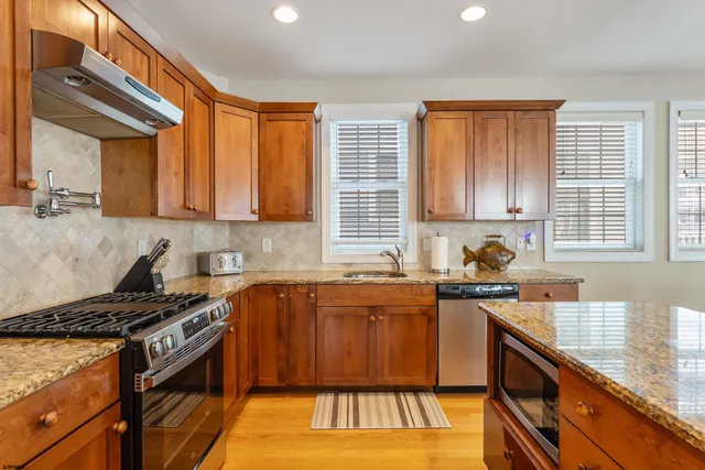 a kitchen with granite countertop stainless steel appliances a sink stove top oven and cabinets