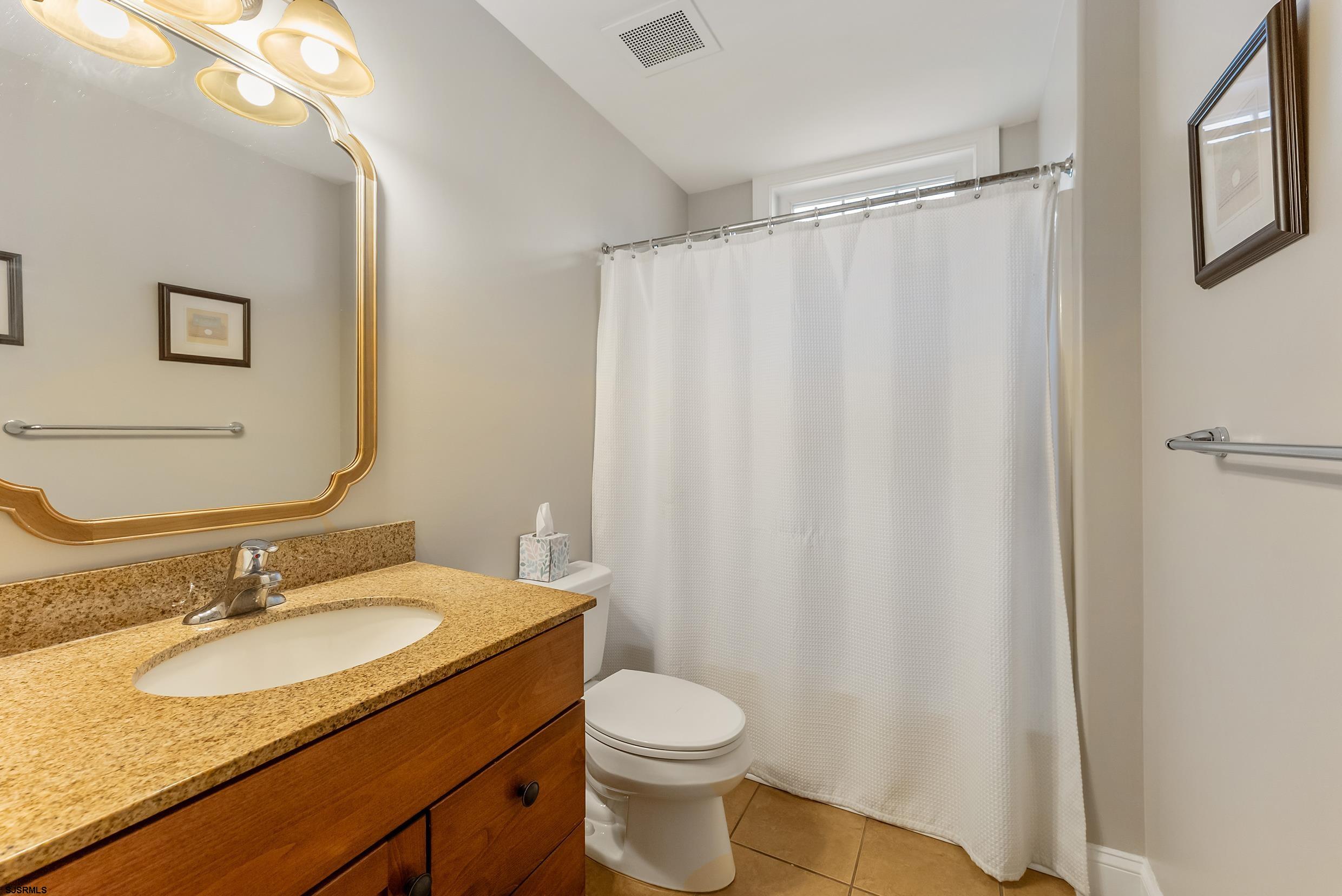 909 East 4th Street, Unit 1 Ocean City, NJ 08226 - Photo 19 of 47 a bathroom with a granite countertop sink toilet and a mirror