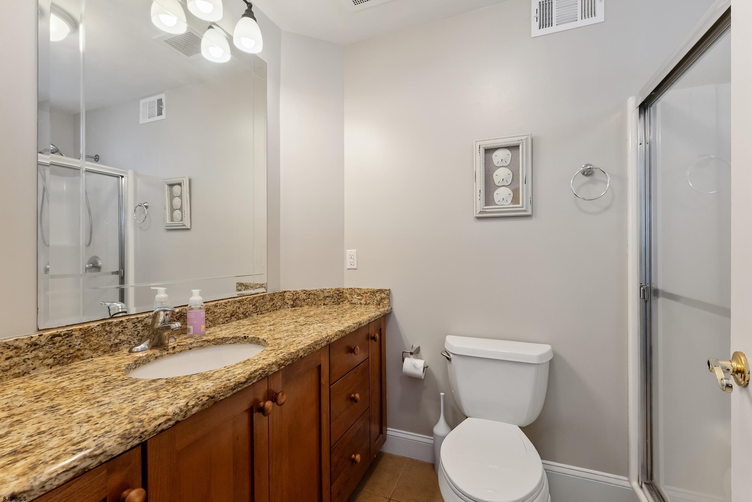 909 East 4th Street, Unit 1 Ocean City, NJ 08226 - Photo 30 of 47 a bathroom with a granite countertop toilet sink and mirror