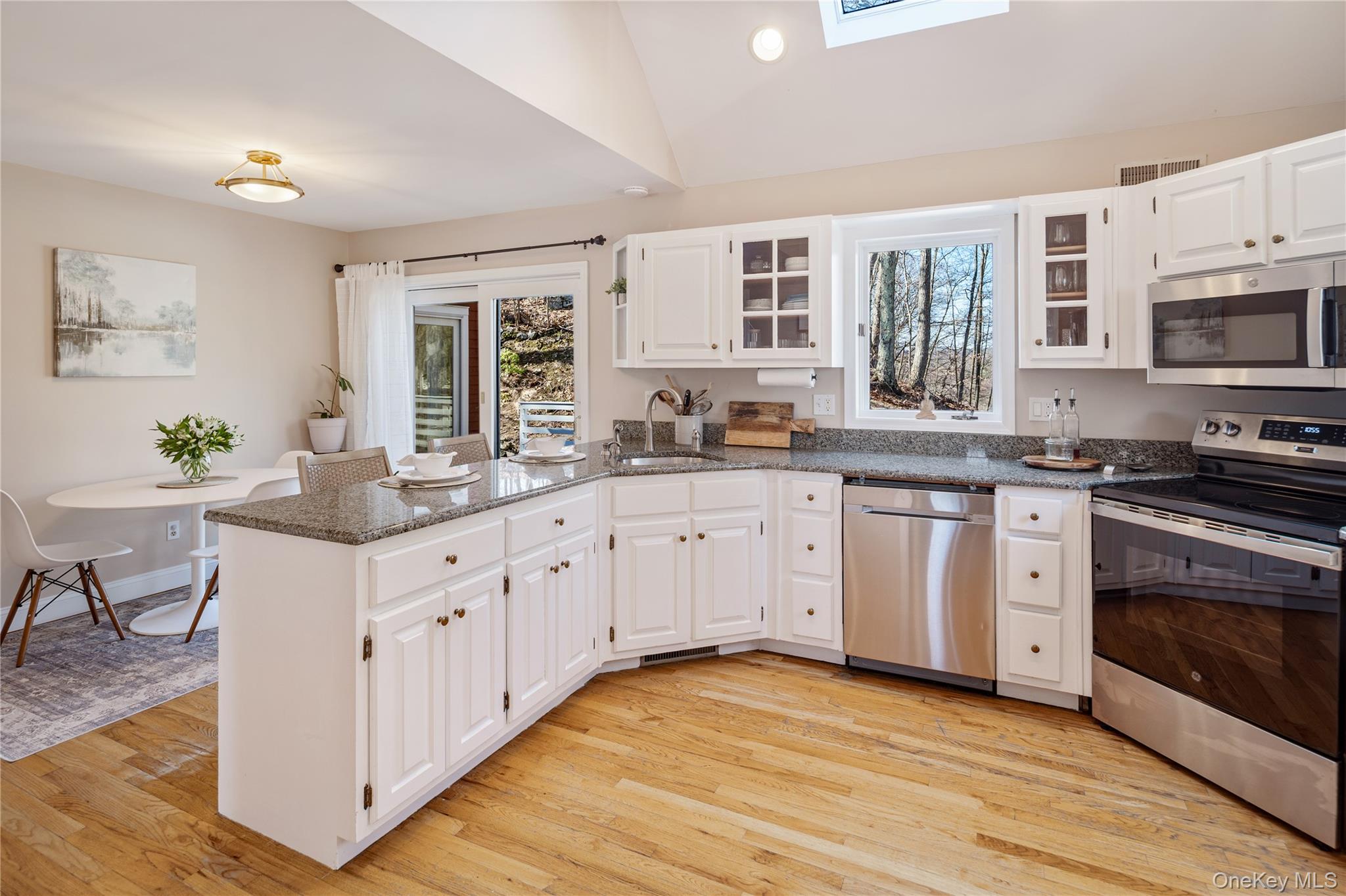 15 Cross Road Cortlandt Manor, NY 10567 - Photo 18 of 50 a kitchen with stainless steel appliances granite countertop a stove a sink dishwasher and white cabinets with wooden floor
