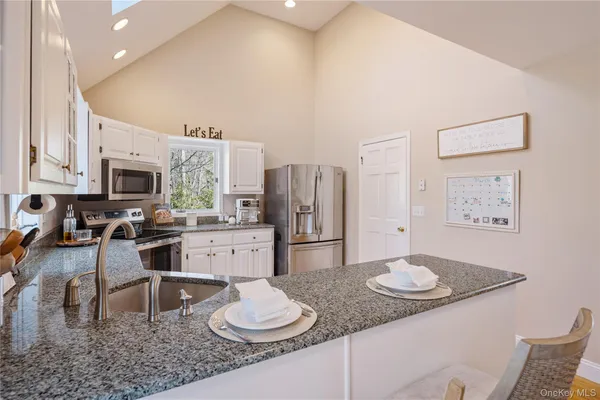 a kitchen with stainless steel appliances granite countertop a stove a refrigerator a sink a dining table and chairs with wooden floor