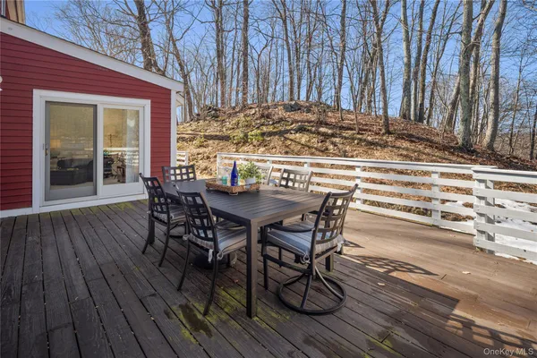 a view of a roof deck with table and chairs couches with wooden floor and fence
