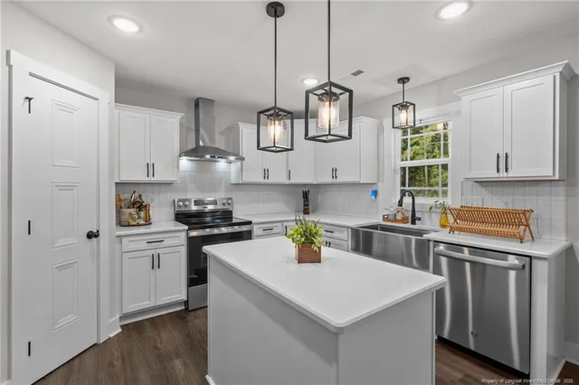 a kitchen with stainless steel appliances granite countertop a sink a stove a refrigerator and white cabinets with wooden floor